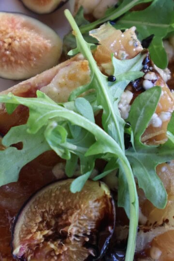 Fig gorgonzola flatbread cut into pieces with fresh figs, arugula and balsamic drizzle