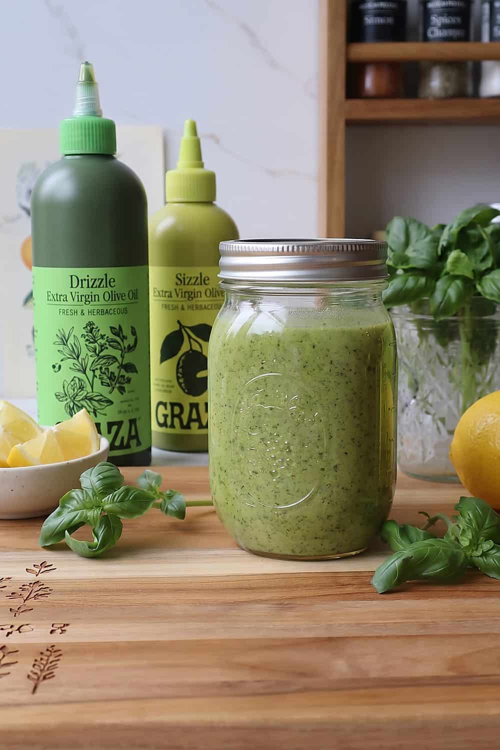 Basil pesto in a mason jar with Graza Drizzle and Sizzle olive oil bottles